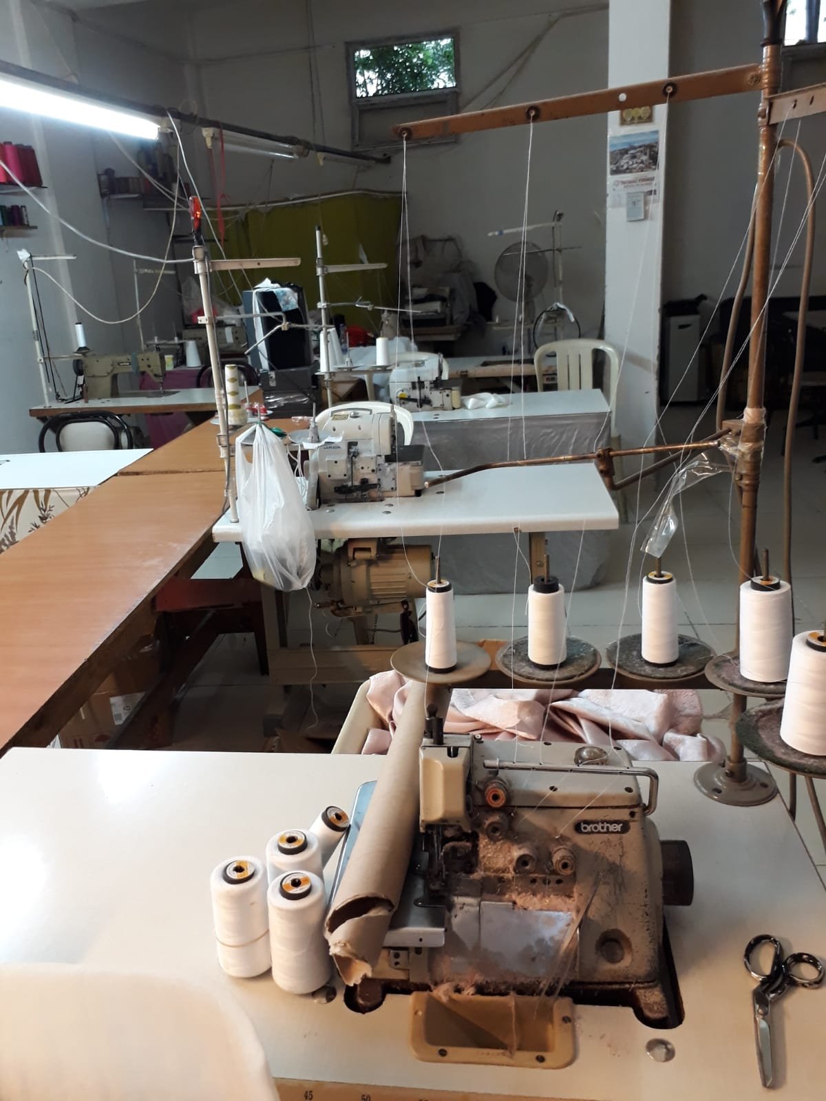 Dokuma Tekstil atölyesinde overlok makineleri ve iplik konileri