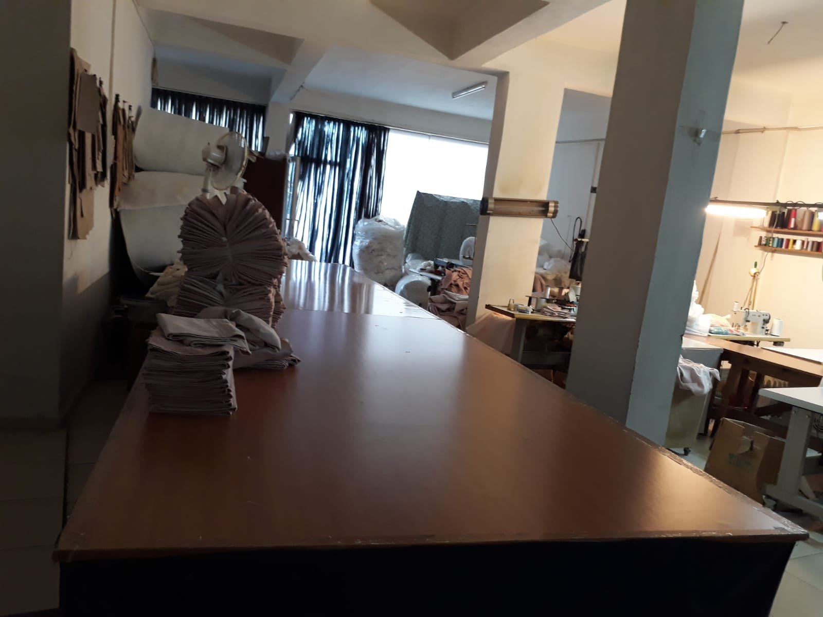 Atölyede kesim masası üzerinde katlanmış kumaşlar